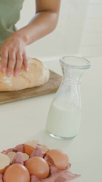 Vertical video: Slicing cook in green top preparing breakfast on counter, with avocado, bread, eggs