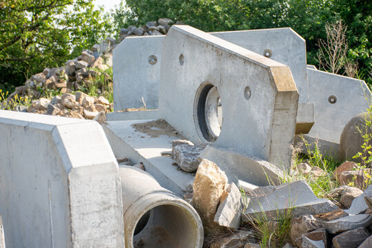 Heavy precast concrete drainage elements and pipes stored on a construction site, municipal sewage infrastructure development components.Reinforced concrete headwalls with circular pipe openings 