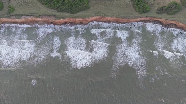 Orilla del mar con olas chocando contra acantilado, naturaleza costera vista cenital a&eacute;rea