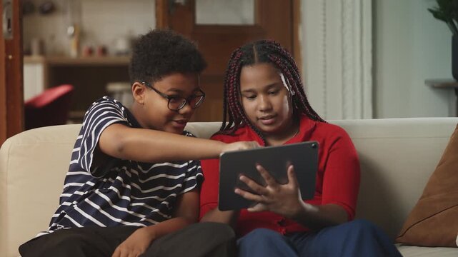 Black boy and girl playing a game on a tablet, educational app for children