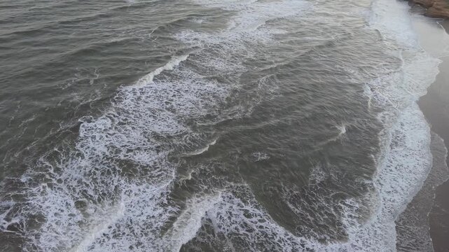 Olas del mar rompiendo en la orilla de la playa, vista a&eacute;rea de dron en paisaje costero natural