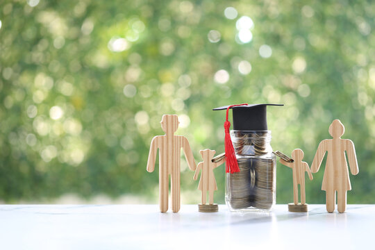 Wooden family figures standing with a jar of coins topped with a graduation cap, symbolizing education savings, college fund planning, financial investment for children and academic future.