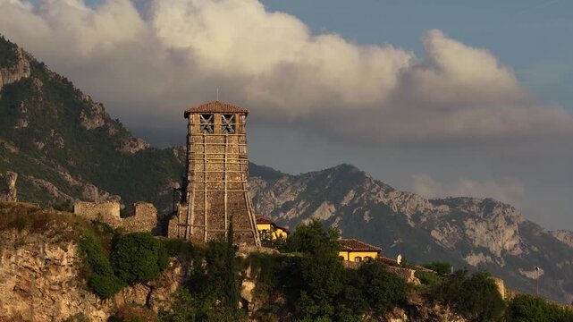 Aerial view of the historic Kruje Castle clock tower under restoration with wooden scaffolding against a backdrop of mountains and clouds in Kruje, Durres County, Albania.