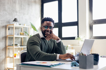 Obraz premium Smiling man working on laptop in modern office
