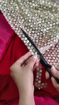 Close-up of hands cutting decorative embroidered lace for costume making, showcasing textile craftsmanship, garment design, tailoring process, and handmade fashion detailing.