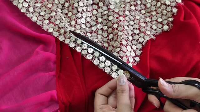 Close-up of hands cutting decorative embroidered lace for costume making, showcasing textile craftsmanship, garment design, tailoring process, and handmade fashion detailing.