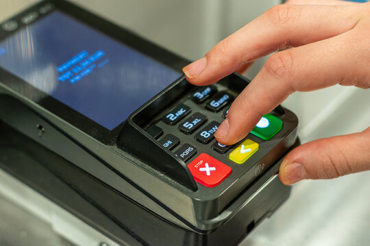 Close up of customer hand entering PIN code on credit card terminal keypad while paying for purchase in store, retail business concept