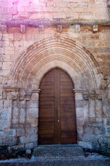 Fototapeta premium Architectural view of the 13th-century Cistercian main portal with pointed archivolts and a wooden door at the Monastery of Santa Maria de Palazuelos in Corcos del Valle, Valladolid, Castilla y Leon