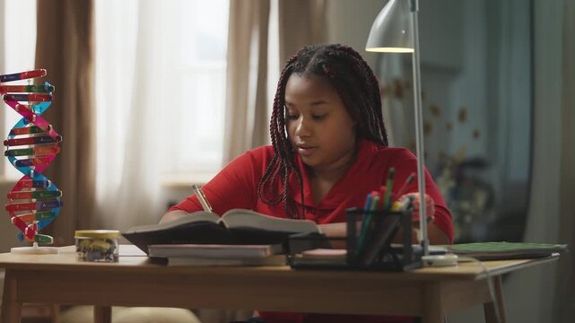 African American girl with braids doing homework and writing in a notebook