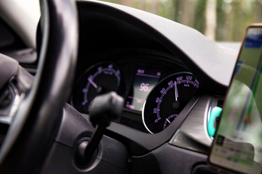 Driving Car With Speedometer Showing Speed and Phone Navigation System During Daytime