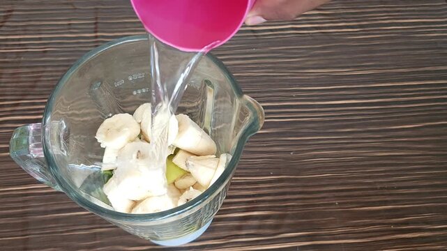 Adding Fresh Banana Pieces Into Blender with Apple and Nopal Cactus Pads