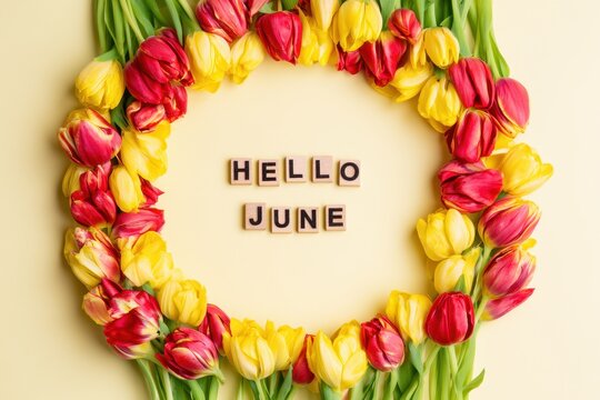 Circular wreath of red and yellow tulips framing the text Hello June made with wooden letter tiles