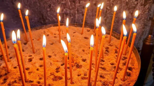 Burning prayer candles stand in a sand-filled holder inside Jvari Monastery, Mtskheta, Georgia