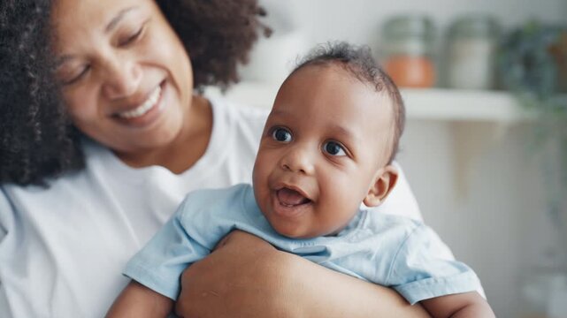 Portrait of cute african infant girl or boy, mother holding baby in hands. Childhood and motherhood, happy family moments, single woman parenting baby, african american ethnicity, mixed race children