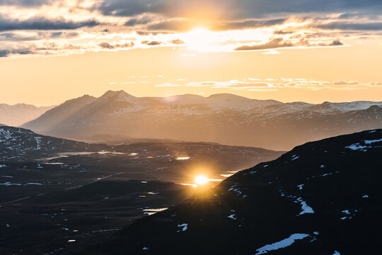 Golden sun setting over a snowy mountain range