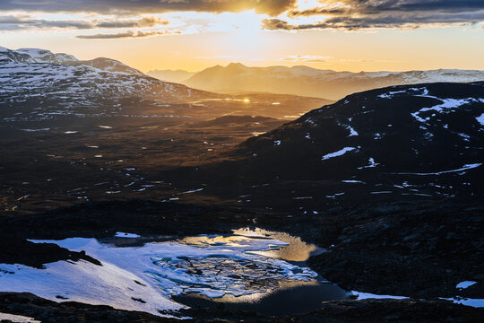 Partially frozen mountain lake beneath midnight sun in Finnish lapland