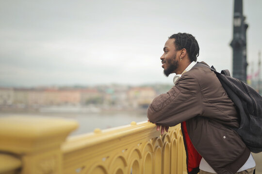 Young black tourist contemplates the cityscape from a bridge