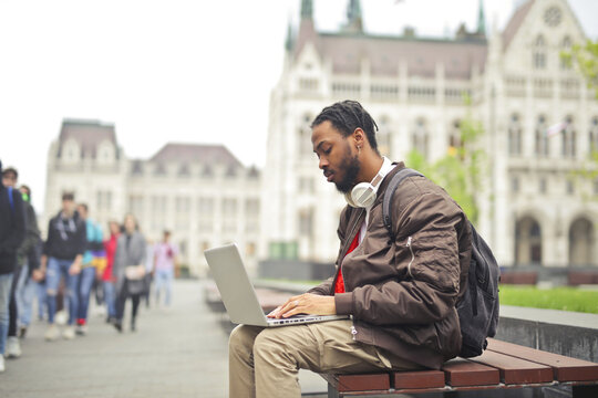 Young man working on a laptop computer in a city square