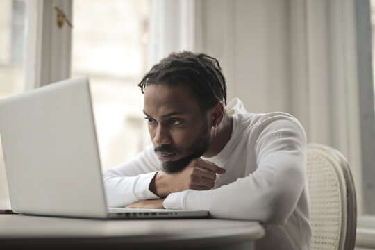 Serious young Black man focused on laptop screen