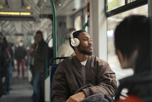 Young man with headphones looking out bus window