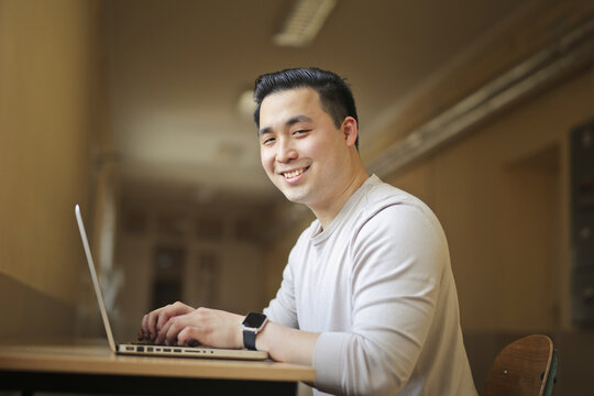 Happy young Asian man using a laptop computer