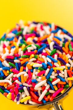 Rainbow Sprinkles in Scoop Against Yellow Background