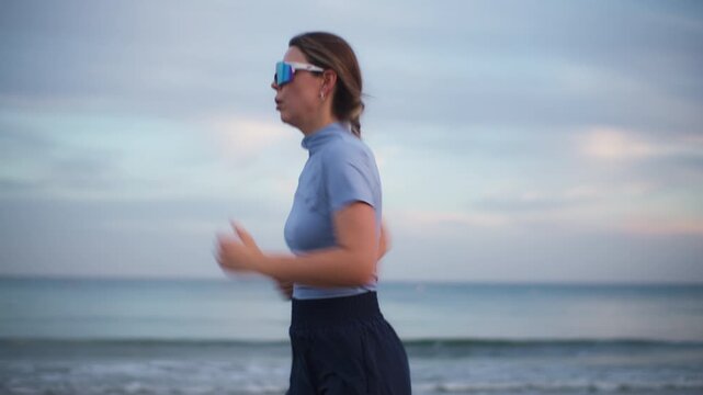 Athletic woman jogging on beach at sunset full body runner training by ocean sea fitness workout healthy lifestyle in beautiful summer landscape