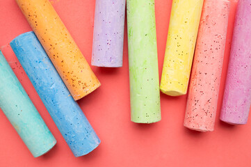 Multicolored chalk sticks viewed from above on pink backdrop. Preschool concept emphasizes early education, playful creativity and visual learning resources for advertising and educational content. © olgaarkhipenko