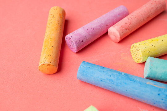 Multicolored chalk sticks viewed from above on pink backdrop. Preschool concept emphasizes early education, playful creativity and visual learning resources for advertising and educational content.