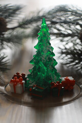 Obraz premium Festive Green Christmas Tree with Gifts and Pine Branches on Rustic Wooden Table