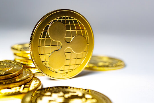  Primer plano de la moneda f&iacute;sica Gold Ripple XRP apoyada en la pila de monedas sobre una superficie reflectante azul, primer plano editorial de la moneda Ripple XRP para noticias