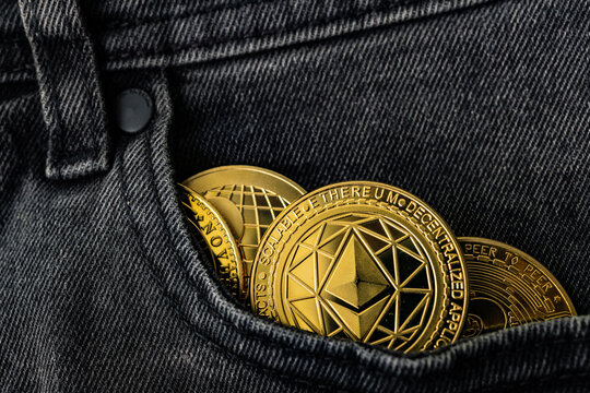 Moneda ETH Ethereum dorada asomando desde el bolsillo de unos jeans de mezclilla oscuros. Moneda Ethereum en el bolsillo de unos jeans; ahorro de criptomonedas y concepto de activo digital 