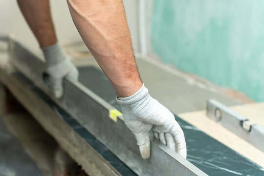 Worker pressing black marble effect tile into place