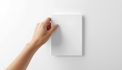 Fototapeta premium Hand touching a blank rectangular paper on a white surface