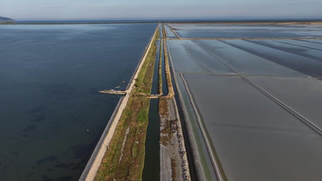 Aerial view of the extensive salt evaporation ponds and dikes at Narta Lagoon under a clear sky in Vlore, Vlore County, Albania.