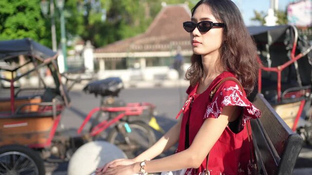 Indonesian Woman Relaxing Near Traditional Pedicabs in Yogyakarta