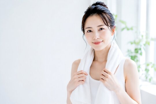 白いタオルを首にかけたナチュラルな女性の美容イメージ