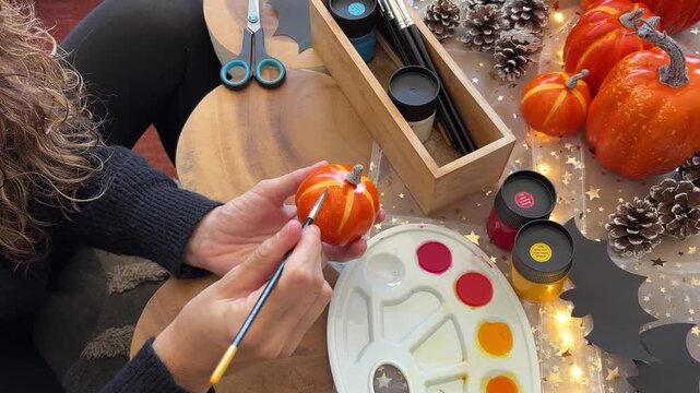 &Oacute;rbita cenital de manos pintando calabaza decorativa Halloween