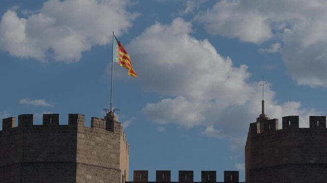 Senyera Flag Waving Above Medieval Stone Battlements at Sunset