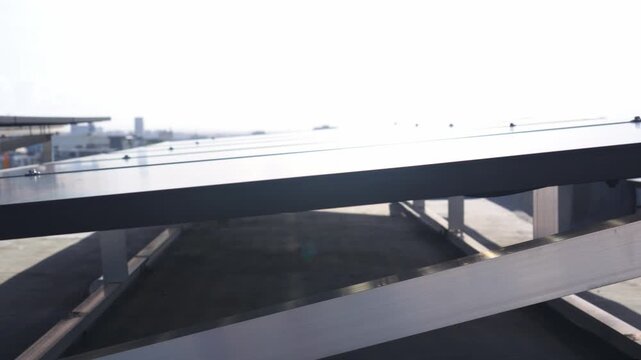 Close-up tracking shot of a modern rooftop solar panel array, revealing the mounting infrastructure and modular design with an urban cityscape in the background