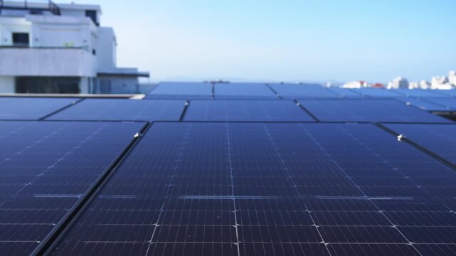 Close-up tracking shot of a modern rooftop solar panel array, revealing the mounting infrastructure and modular design with an urban cityscape in the background