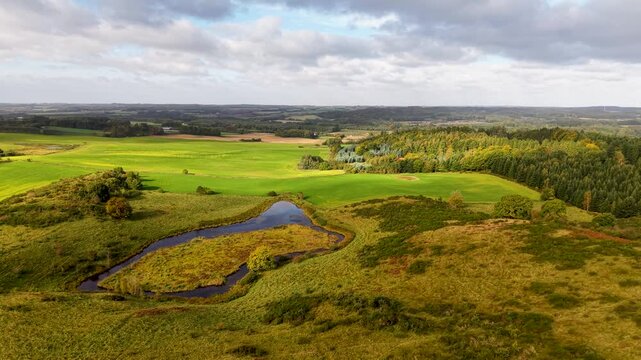 Aerial drone view of ancient Sl&aring;g&aring;rd Banke burial mounds rising from heathland landscape in rural Denmark