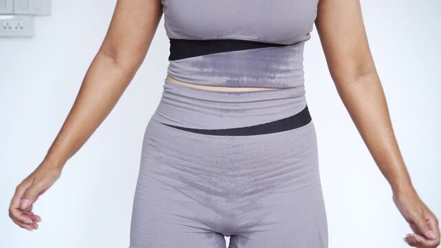sweaty woman in grey activewear doing a squat exercise at home, focusing on lower body workout, glute training, fat burning, sweat production, weight loss, and fitness motivation