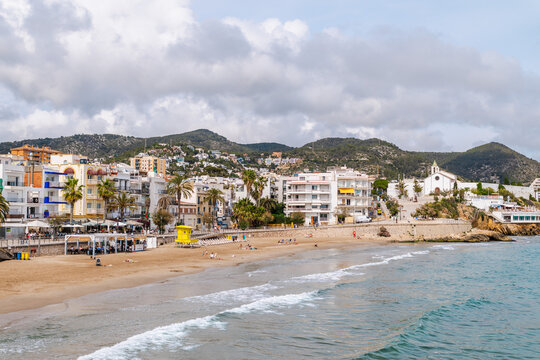 Sitges beach and coastal promenade with Sant Bartomeu church in Sitges Spain