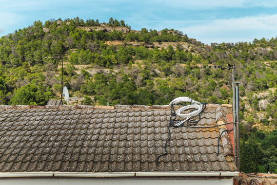 Rural rooftop with television antenna overlooking wooded valley and Mediterranean hills near Margalef village in Catalonia, Spain
