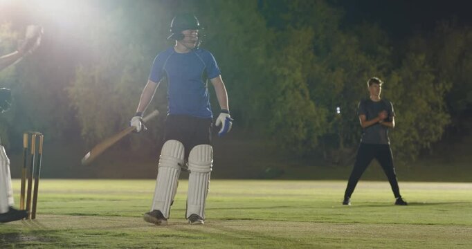Male batsman on cricket pitch responding to bowler's run-up by driving ball, bat scoring runs