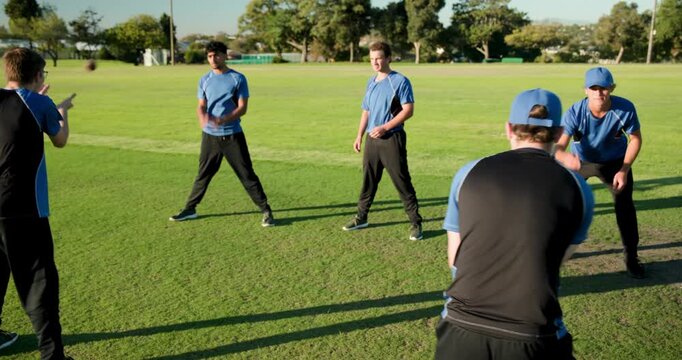 Teen thrower tossing red ball, diverse cricket team training slip catching in park