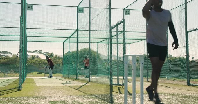 White teenage boy bowling to indian man batting, black man finishing his bowl in nets