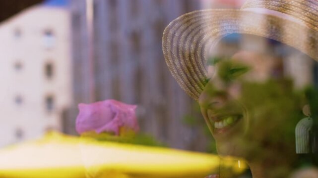 A close-up portrait of a smiling woman holding an ice cream cone. Soft pastel clothing and bangs frame her face, while bright daylight creates a soft reflection in the window. 