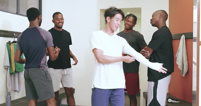 Diverse male friends clapping to welcome asian newcomer entering locker room